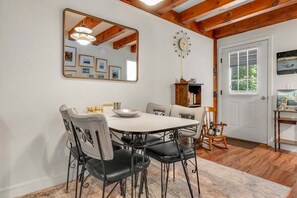 Un comedor con una mesa redonda, sillas, un reloj y un espejo en la pared.