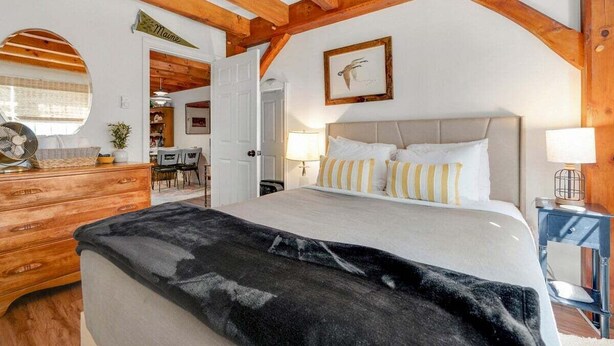 Una camera da letto con un letto, travi in legno, una cassettiera, una scrivania e una sedia.