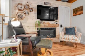 Una sala de estar con televisión, chimenea y dos sillones.