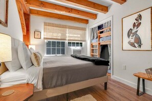 Un dormitorio con una cama, una ventana, una estantería y un cuadro.