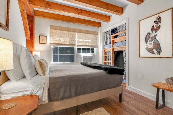 Un dormitorio con una cama, una ventana, una estantería y un cuadro.