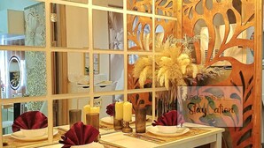 Un comedor con una mesa blanca dispuesta para cuatro personas, adornada con servilletas rojas, velas y un centro de mesa decorativo.