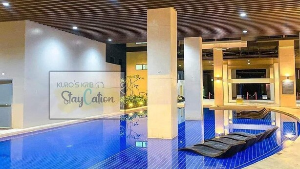 Una piscina interior con suelo de baldosas y techo de madera.