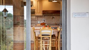 A kitchen with wooden cabinets, a tiled backsplash, and a dining area with wooden chairs and a table. - Apartment for 2/3 guests with panoramic patio, pool and Wi-Fi (Toscana)
