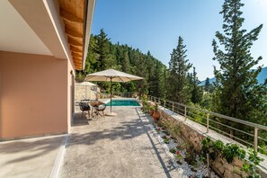 A pool area with a table and chairs, surrounded by a stone wall and potted plants. - Kipseli Villa, Overlooking Vassiliki bay (Lefkada)