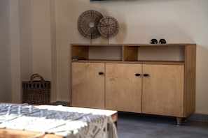 Un meuble en bois avec deux portes et une étagère, un panier en osier et une paire d’écouteurs noirs posés sur le dessus.