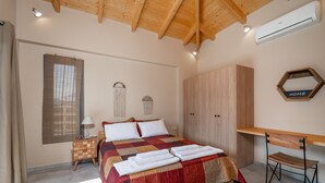 A bedroom with a wooden ceiling, a bed with a red and beige quilt, a wooden wardrobe, a desk with a chair, and a window with blinds. - Kipseli Villa, Overlooking Vassiliki bay (Lefkada)