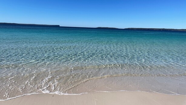 Ein Strand mit klarem türkisblauem Wasser und einem Sandstrand.