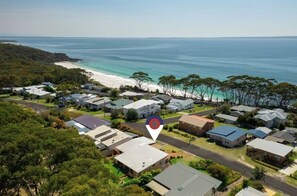 An aerial view of a coastal residential area with houses, a beach, and a clear view of the ocean. - The Golden Retreat @ Hyams Beach - Pet Friendly, Linen & Wifi provided (Hyams Beach)
