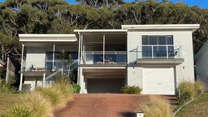Ein modernes, zweistöckiges Haus mit Garage, überdachter Terrasse und Blick ins Grüne.
