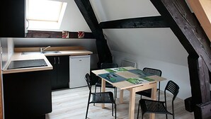 Una cocina compacta con ventana, una mesa de comedor con sillas y un refrigerador pequeño.