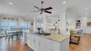 A spacious kitchen with a large island, white cabinetry, and a ceiling fan. - Oceanfront Mega Estate | Private Pool, Sleeps 25, Game Rooms & Decks (Isle of Palms)