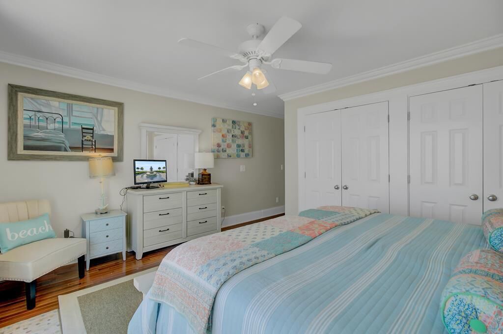 A bedroom with a bed, nightstands, a desk, a chair, and a ceiling fan.