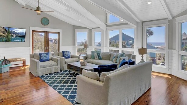 A spacious living room with a high ceiling, large windows, and a view of the ocean. - Second Star | Oceanview Coastal Showpiece with Private Pool (Isle of Palms)