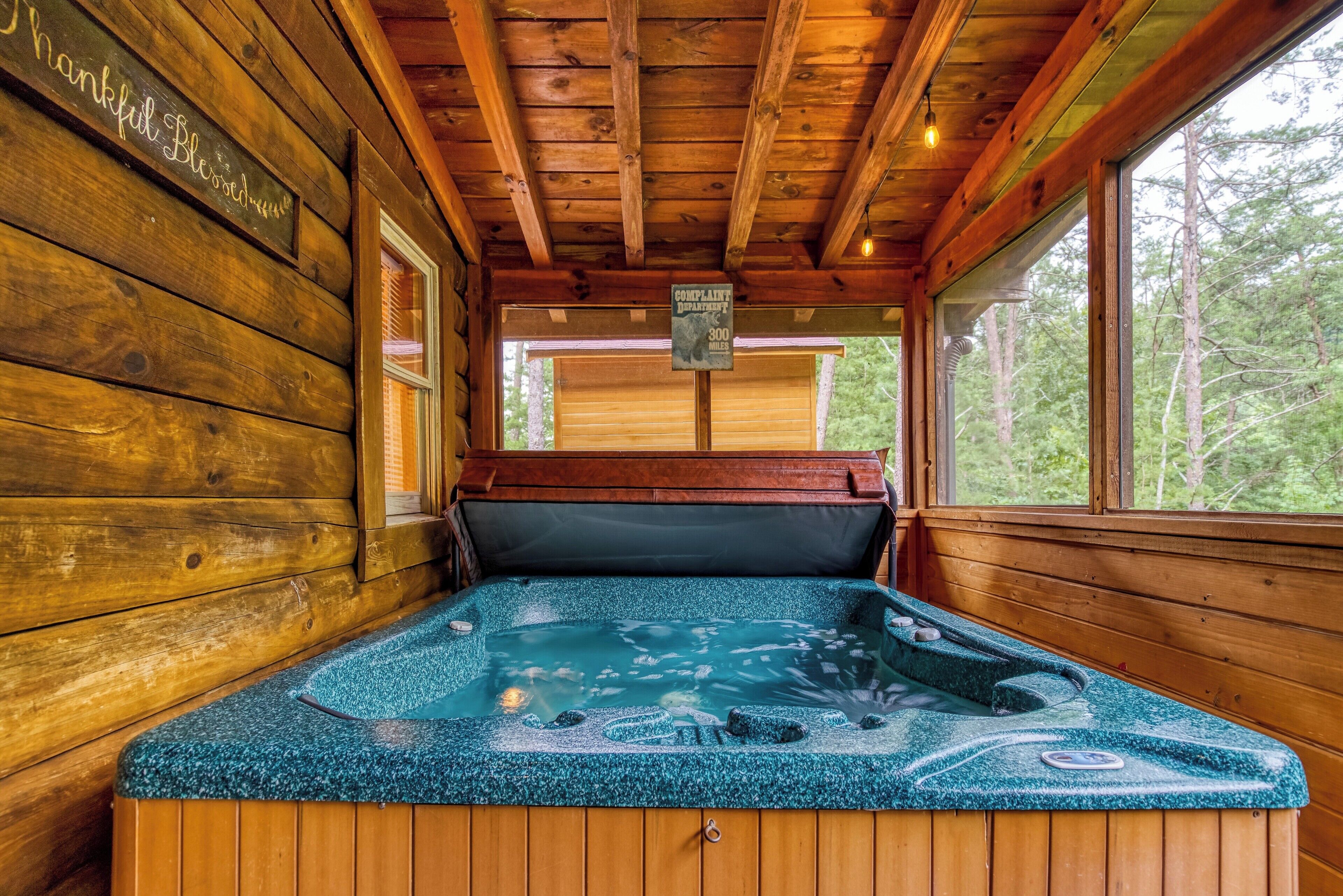 Une cabane en bois dotée d’un bain à remous, de murs en bois et de grandes fenêtres.