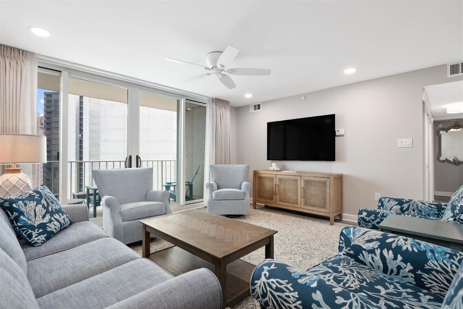 Una sala de estar moderna con un sofá, una mesa de centro, un televisor y un ventilador de techo.
