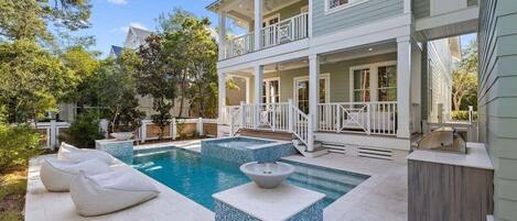 A two-story house with a swimming pool, outdoor seating, and a covered porch.