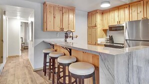 Eine moderne Küche mit Holzschränken, einer Marmorarbeitsplatte und einem Edelstahl-Kühlschrank.