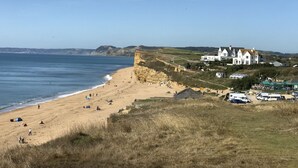 A coastal beach with a large white building, likely a hotel, adjacent to the shore. - The Billy Shed  - Eype, Bridport (Bridport)