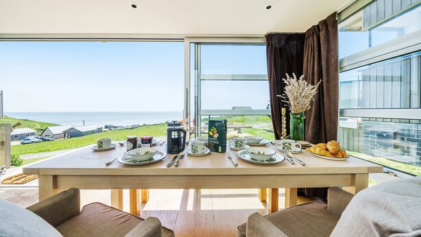 A dining area with a table set for breakfast overlooking a scenic view. - The Billy Shed  - Eype, Bridport (Bridport)