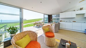 A modern kitchen with white cabinets and a large window overlooking a grassy area. - The Billy Shed  - Eype, Bridport (Bridport)