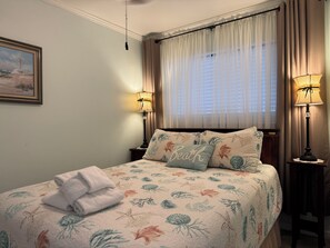 A neatly made bed with a floral bedspread, two bedside lamps, and a framed picture on the wall.