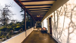 A covered corridor with a bench and a table, leading to a door. - Seclude Shimla Taraview (Shimla)