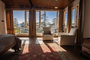 A bedroom with a large window, a bed, a chair, and a dresser. - Seclude Shimla Taraview (Shimla)