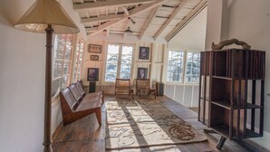 A room with a wooden bench, a lamp, a rug, and a bookshelf. - Seclude Shimla Taraview (Shimla)
