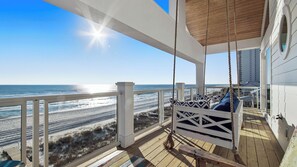 Una terraza de madera con una silla mecedora con vista a la playa.