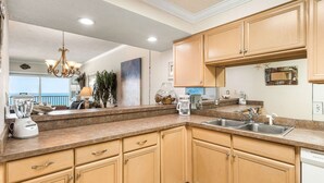 A modern kitchen with wooden cabinets, granite countertops, a built-in dishwasher, and a coffee maker.