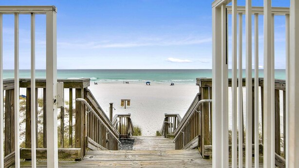 A wooden staircase leading to a beach with a clear view of the ocean.