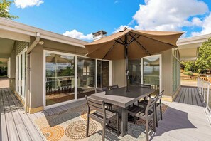 Un patio techado al aire libre con mesa y sillas, puertas correderas de vidrio y piso estampado.