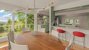 A dining area with a wooden table, white chairs, and a modern chandelier.