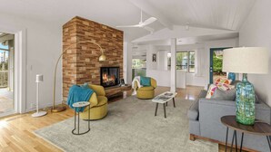 A modern living room with a brick fireplace, two yellow armchairs, a grey sofa, a round coffee table, and a floor lamp.