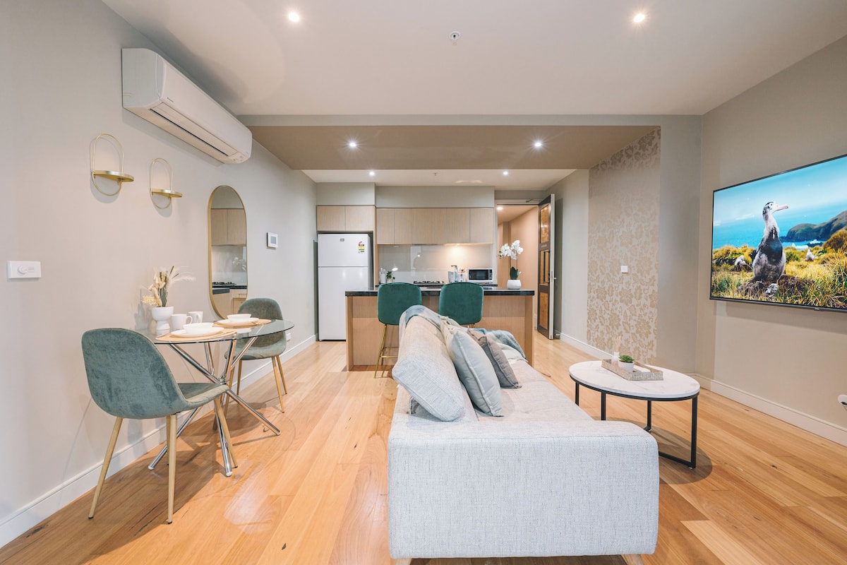 Una sala de estar moderna con sofá, mesa de comedor, sillas y una cocina al fondo.