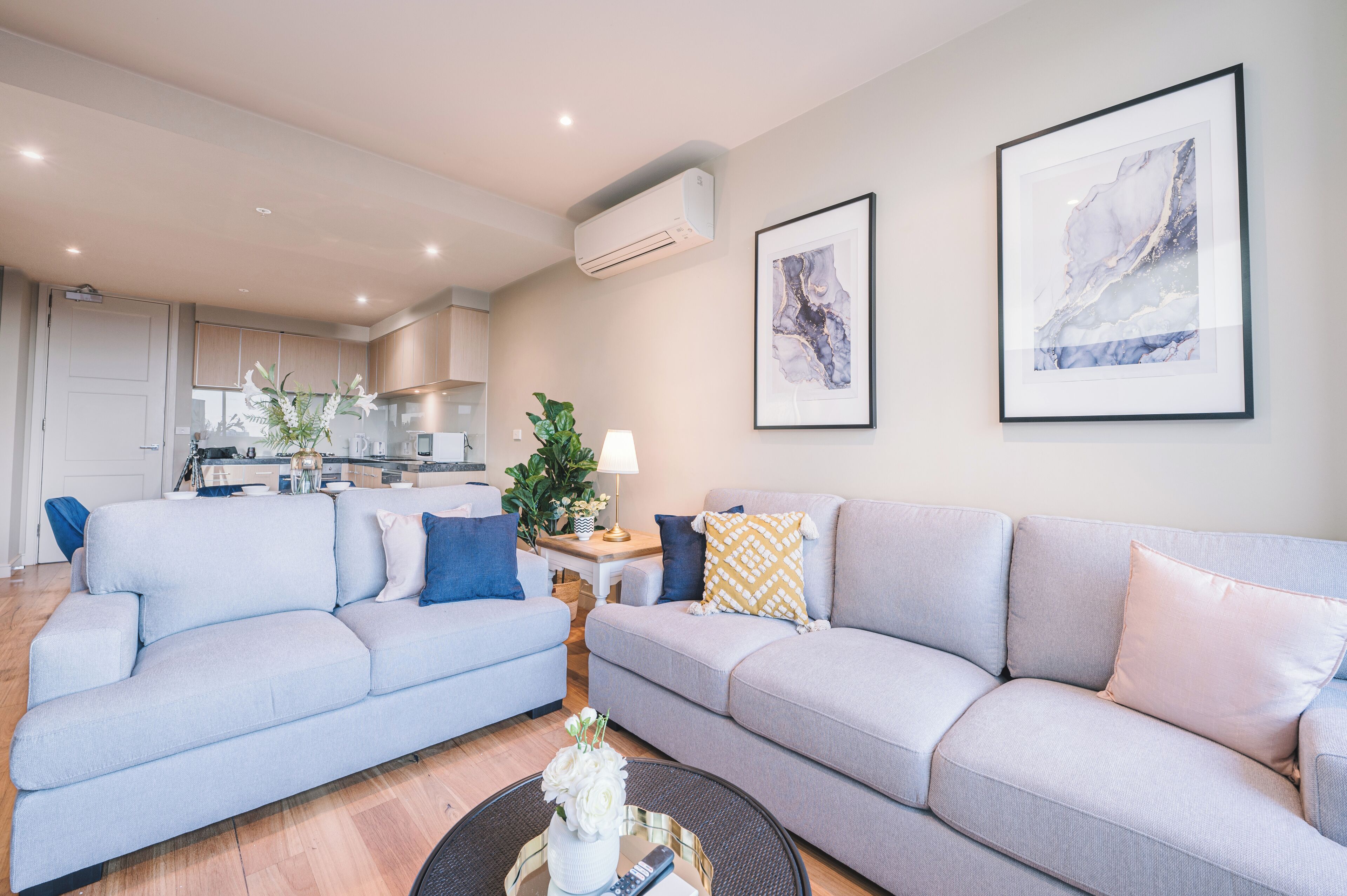 A modern living room with two sofas, a coffee table, and a kitchen in the background.