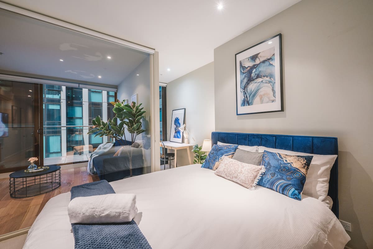 Una habitación de hotel moderna con una cama grande, un escritorio y un ventanal que da a un balcón.
