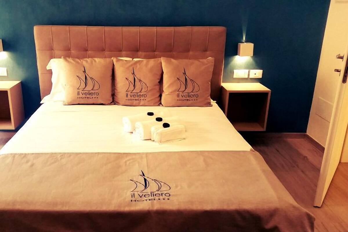 A hotel room with a bed, pillows, and a blanket.