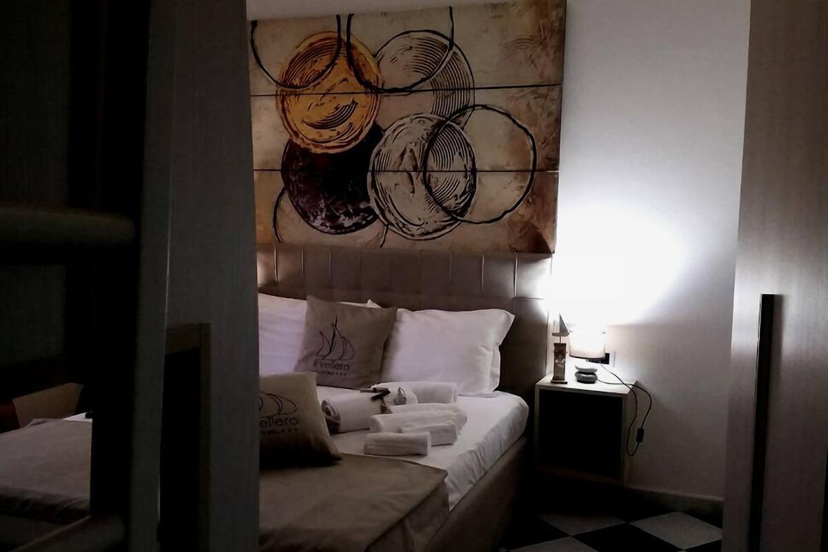 A hotel room with a bed, a nightstand, and a wall with a circular pattern.