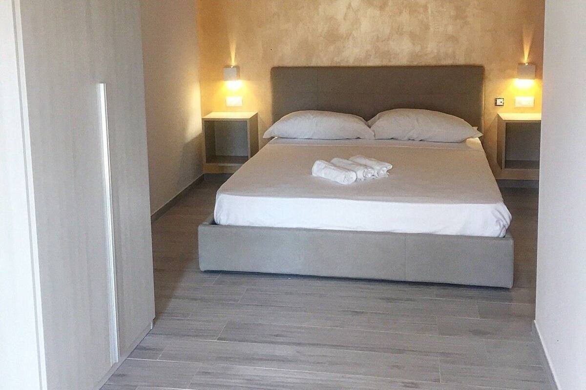 A bedroom with a large bed, two bedside tables, and a textured wall.