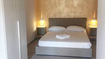 Une chambre à coucher avec un grand lit, deux tables de chevet et un mur à texture.