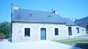 Un bâtiment en pierre avec un toit gris, une porte et deux fenêtres.