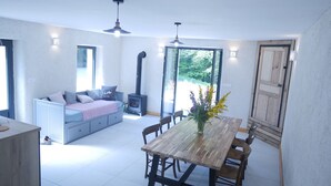 Un salon moderne comprenant un canapé, une table à manger avec des chaises, une cheminée et de grandes fenêtres.