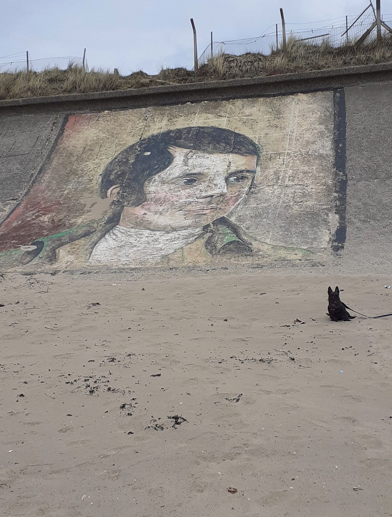 Eine Wand mit einem Wandgemälde, das eine Person und einen Hund an der Leine zeigt.