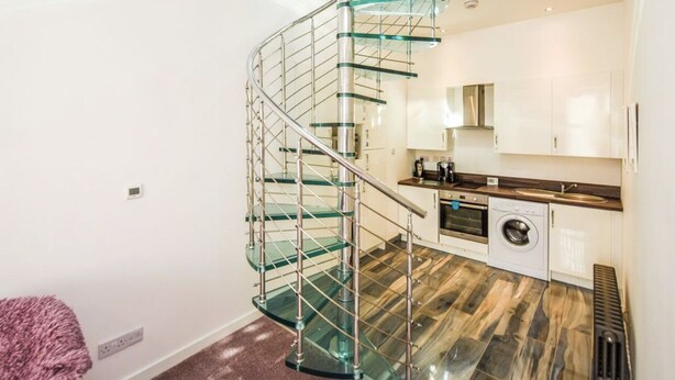 Una cocina moderna con una escalera en espiral de cristal.