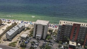 A coastal hotel with a parking lot, beach access, and ocean views.