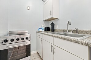 A kitchen with a built-in oven, a double sink, and white cabinets.