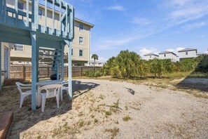 A beach house with a covered patio area, a sandy yard, and a view of neighboring houses. - Cute cottage across from the Gulf (Gulf Shores)