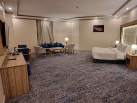 Une chambre d’hôtel avec un lit, un bureau, un canapé et une chaise.